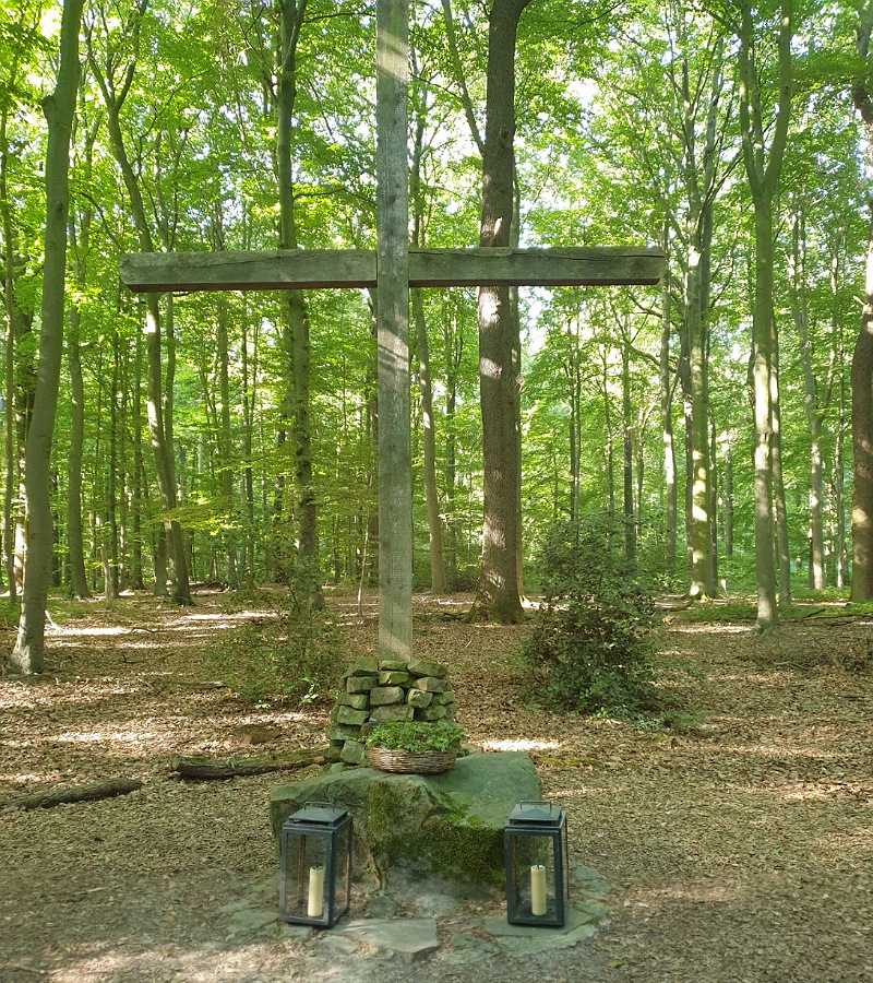 Gedenkstätte mit großem Holzkreuz und Kerzen bei Tag im Friedwald Sehnde