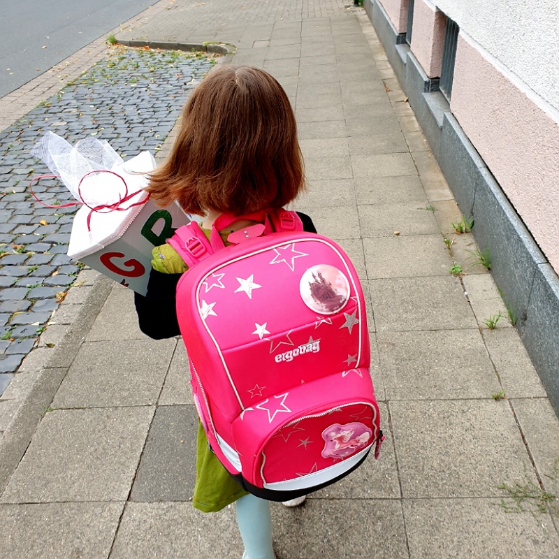 Kind mit Schulranzen und Schultüte auf dem Weg zur Einschulungsfeier