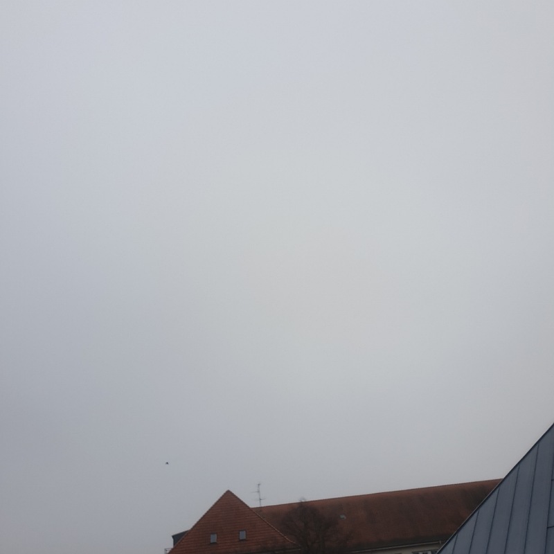 grauer, verhangener Himmel über einem Häuserdach